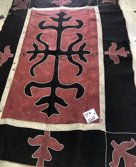 Red-and-black Chechen felt carpet with branching symmetrical shapes outlined in pale trim and smaller motifs around its border.